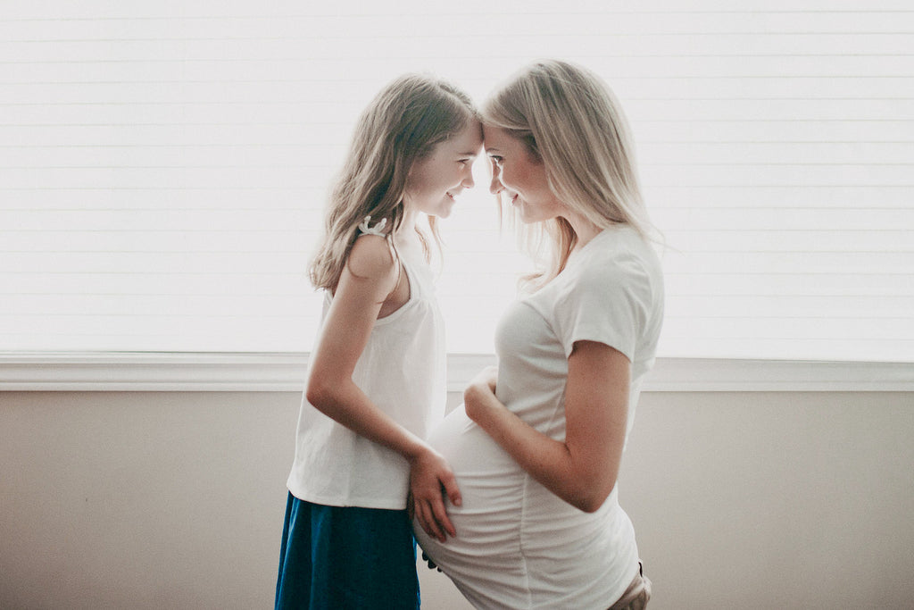 Pregnant woman and her daughter holding pregnant belly unconditional love
